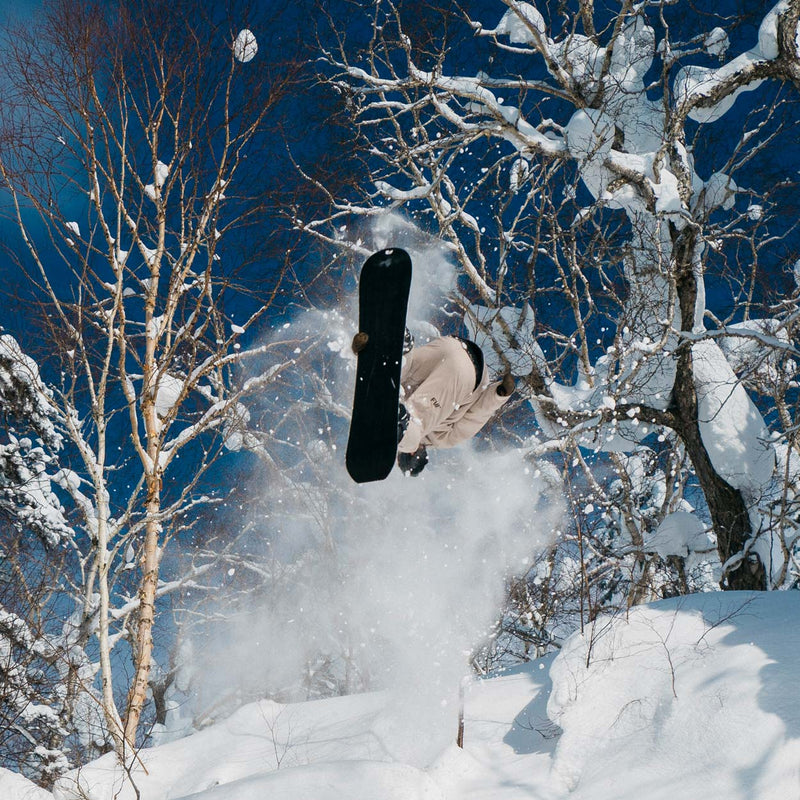 Freeride snowboarder jumping and doing a grab with Cadet snowboard by United Shapes