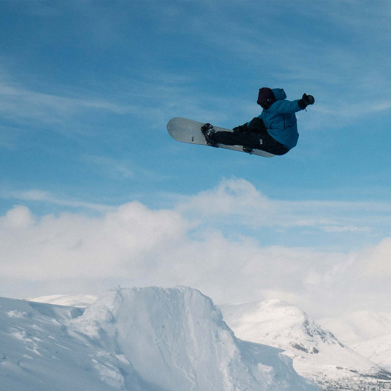Snowboarder jumping and doing a grab with the Horizon united shapes snowboard